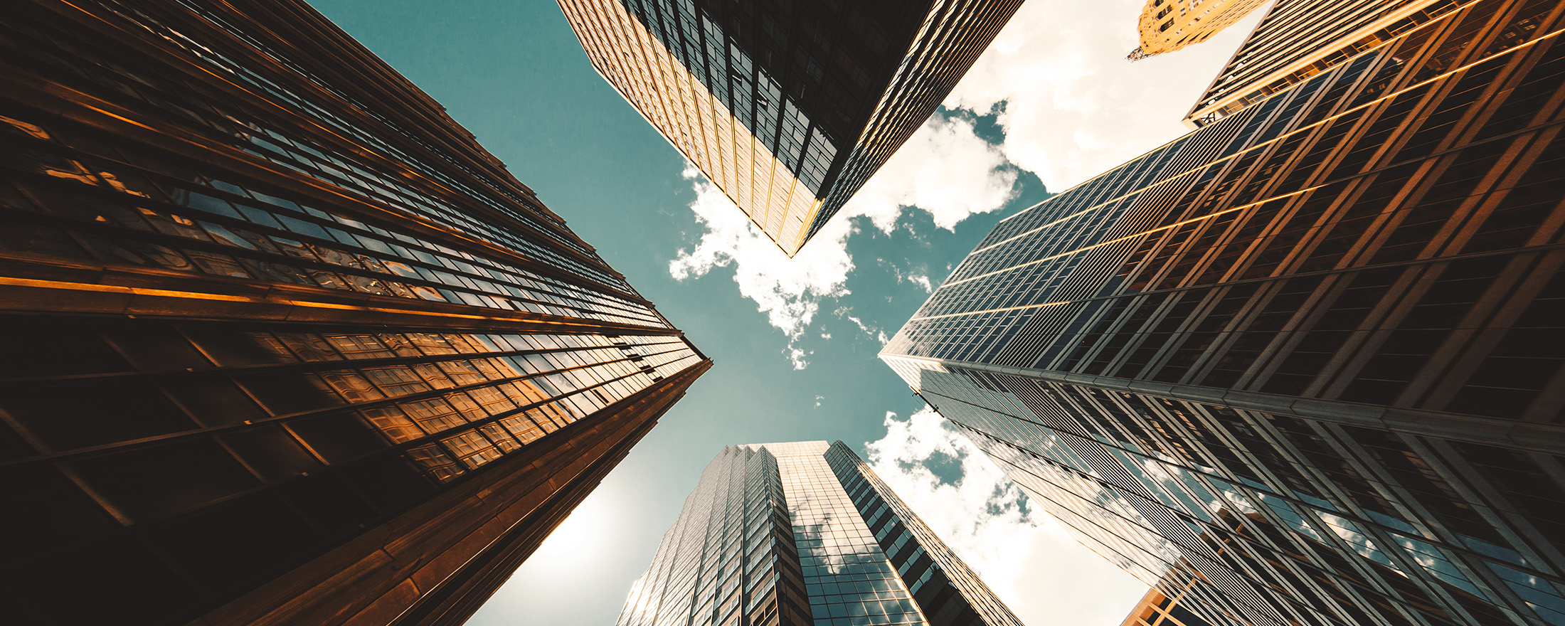 Worms eye view of skyscrapers against a blue cloudy sky