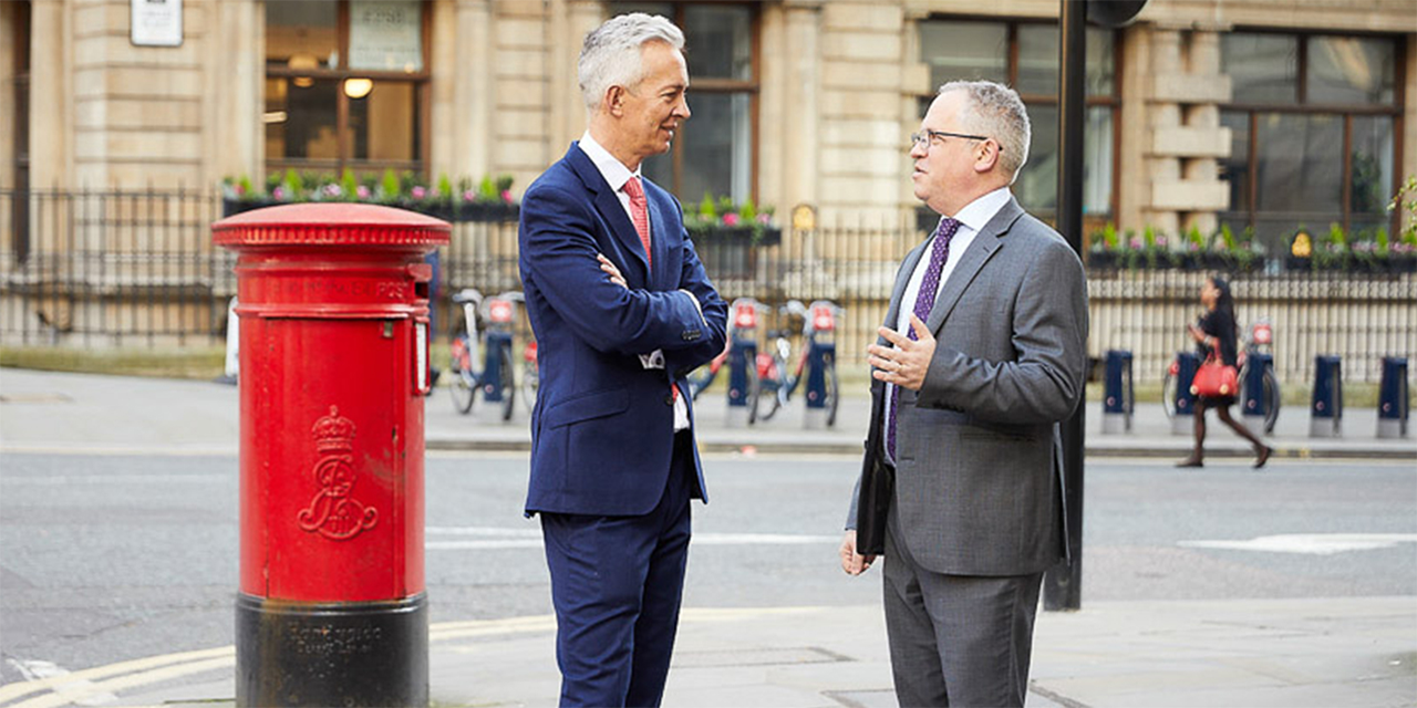 Two professional men talking on a London street corner.