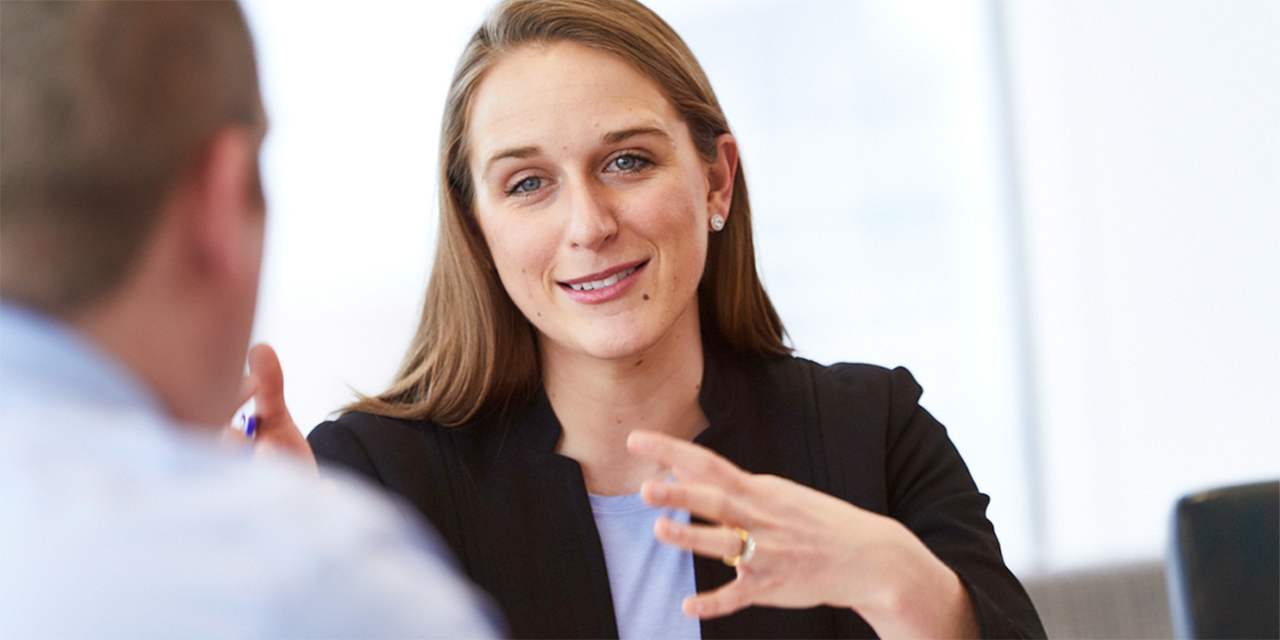 Female Baird associate talking to a man at a conference table.